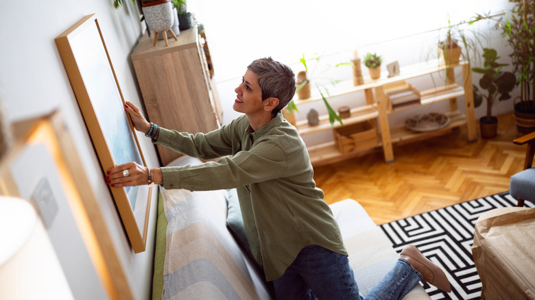 Woman decorating her home with a new painting