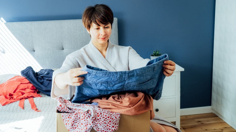 Woman examining clothes on bed