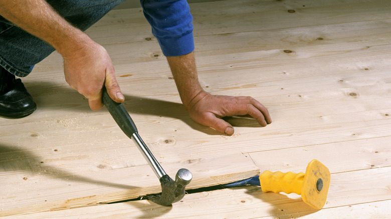 Handyman opening up floor board