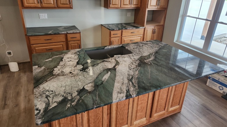 A kitchen with wood cabinets and green quartzite countertops