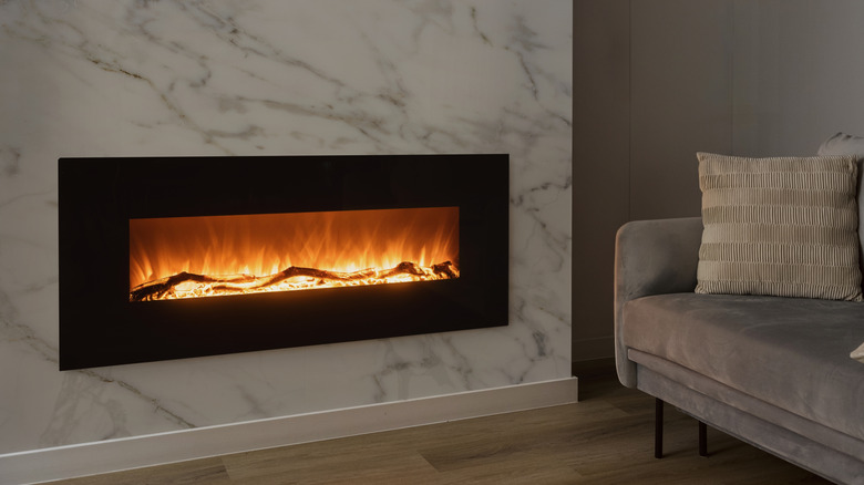 A marble fireplace next to a gray couch