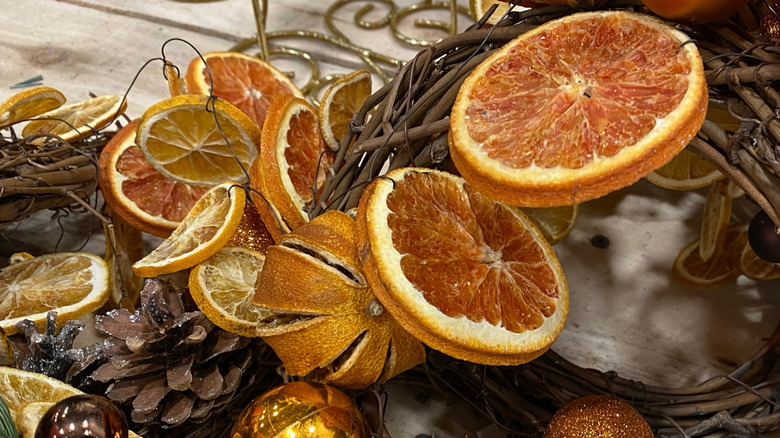 dried orange slices and pinecones with glitter on top of some grapevines