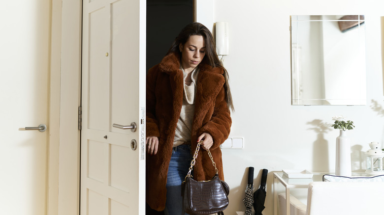 Woman wearing a faux-fur coat walking through the door of her home