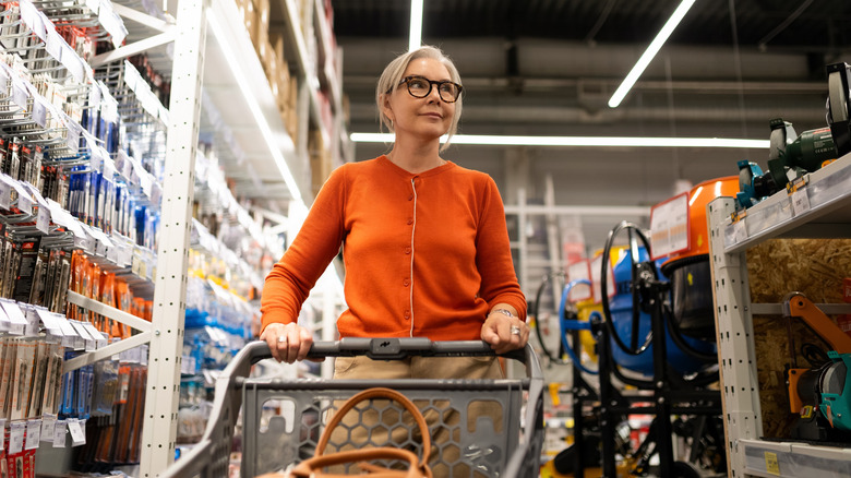 person pushing cart through aisle of home improvement store