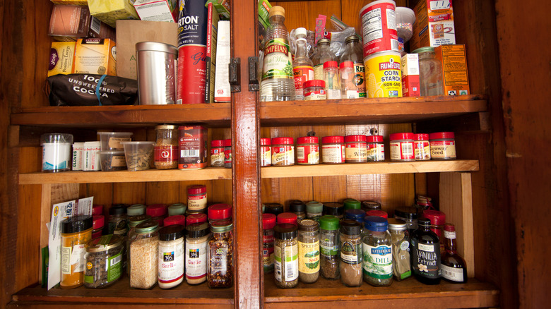 A cluttered spice cabinet jammed with different spices and ingredients