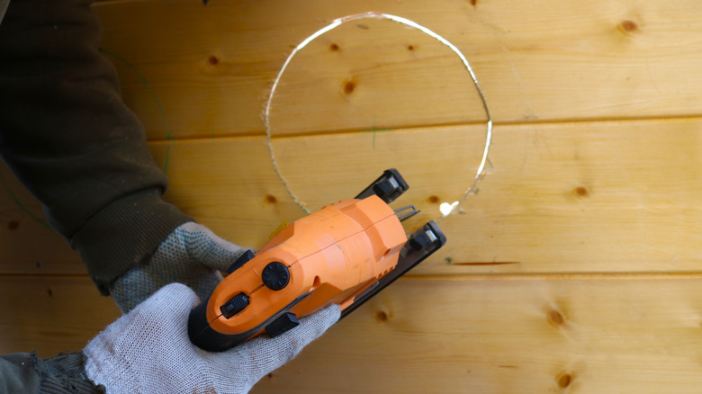 Person cutting a hole out of wood with a jigsaw