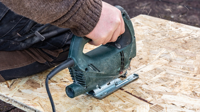 Person cutting a hole in wood with a jigsaw