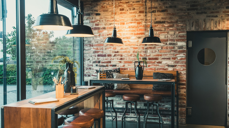 A kitchen with industrial-style furniture and fixtures, an exposed brick wall, and a large window.