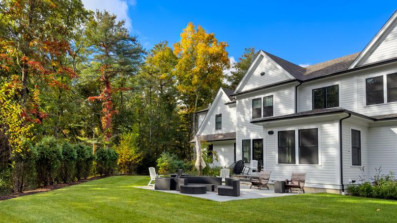 Backyard of a white house with fall foliage