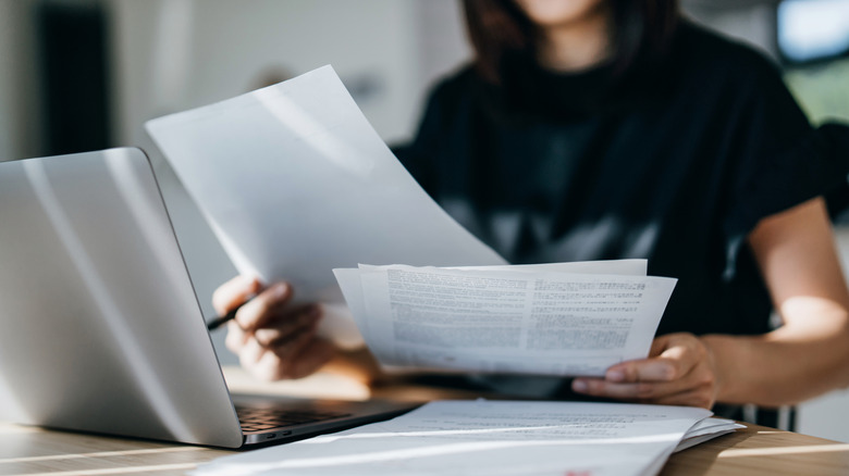 Woman looking at sheets of paperwork at a table or desk