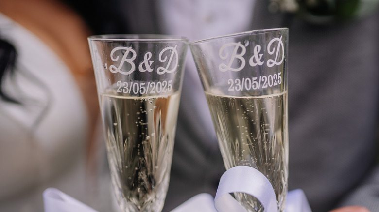 Two champagne flutes with matching custom-engraved initials and an anniversary date.