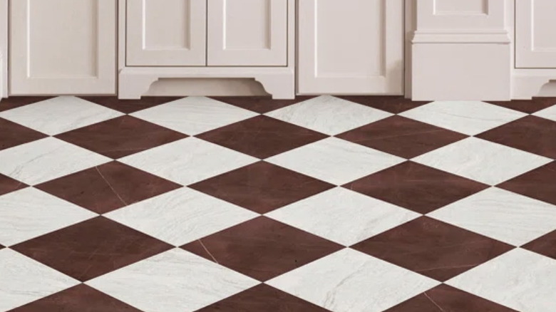A burgundy and white checkerboard tiled floor and white cabinets