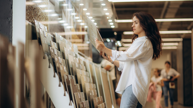 A woman examines tile options in a store