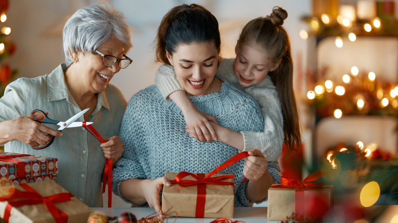 Multigenerational family wrapping Christmas presents among festive decorations