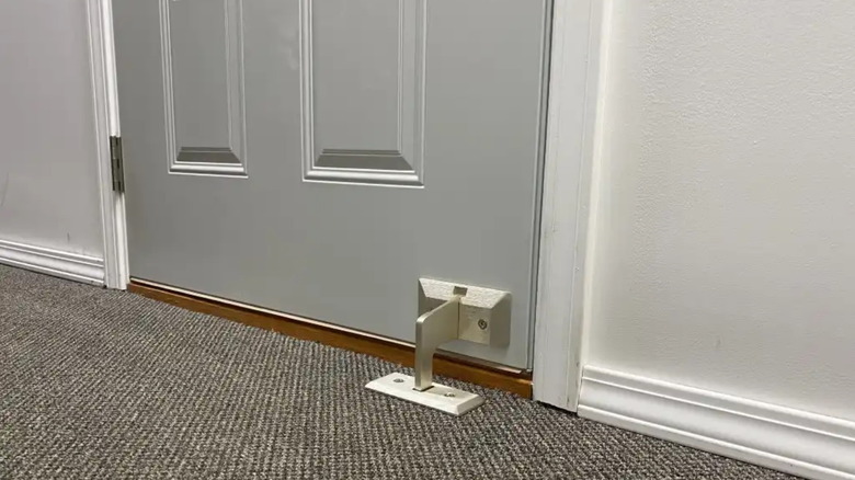 A modern version of a Door Club lock made by Nightlock secures a door in a carpeted room