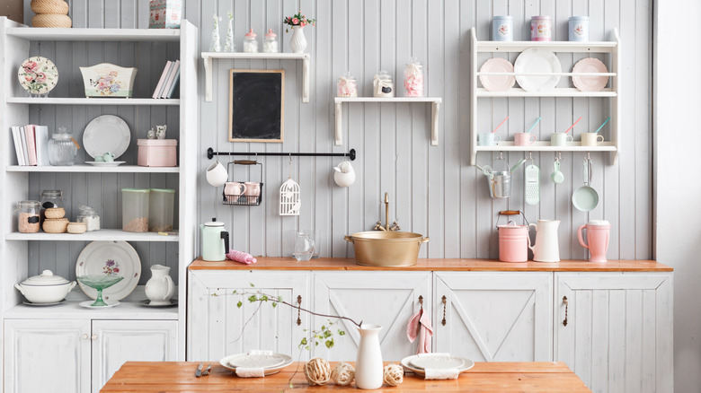 A white kitchen with painted wood paneling behind the sink