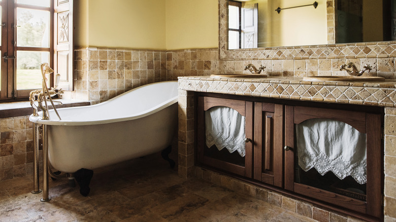 Clawfoot bathtub, wooden drawers, and tile walls in a bathroom