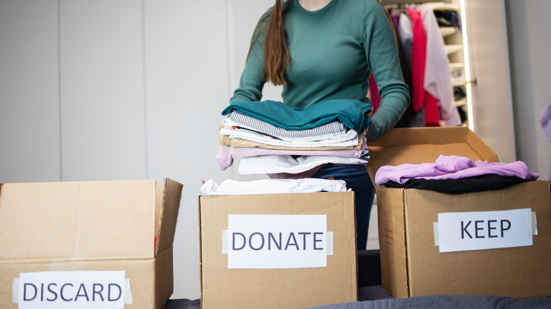 Woman decluttering a closet and putting clothes in discard, donate, and keep boxes