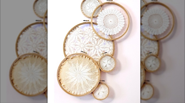Doilies stretched on embroidery hoops hang on a wall
