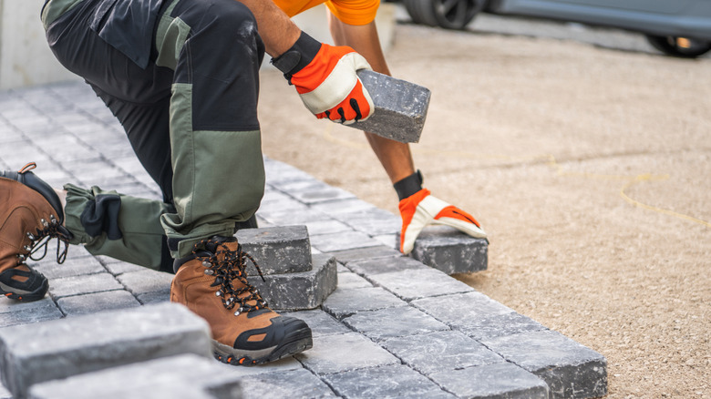 Construction worker installing stones on a driveway