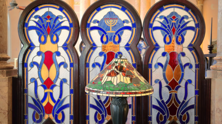Stained glass room divider behind a lamp with a stained glass shade.
