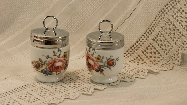 Two egg coddlers on vintage lace background