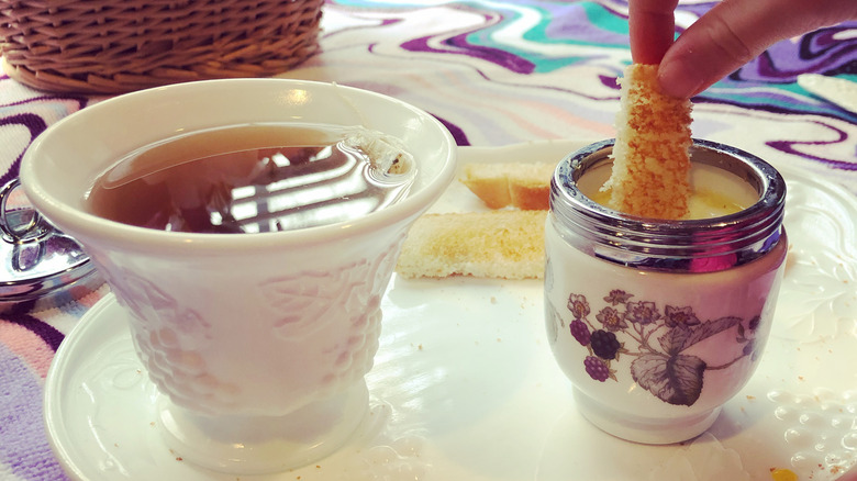 Hand dipping food in egg coddler