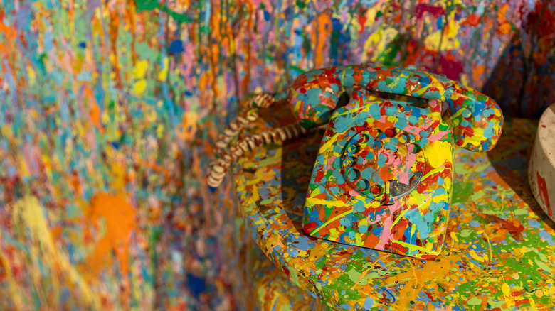 Splatter painted rotary phone on a table with splatter paint on the walls and table