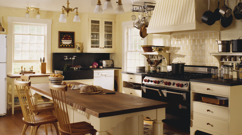 Full vintage looking kitchen with eggshell colored walls and wooden island with wooden chairs