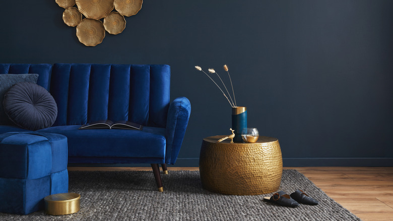 A stylish blue velvet sofa mixed with gold decor pieces