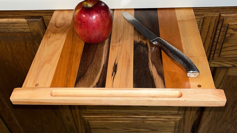 extendable wooden kitchen cutting board with apple and knife on top