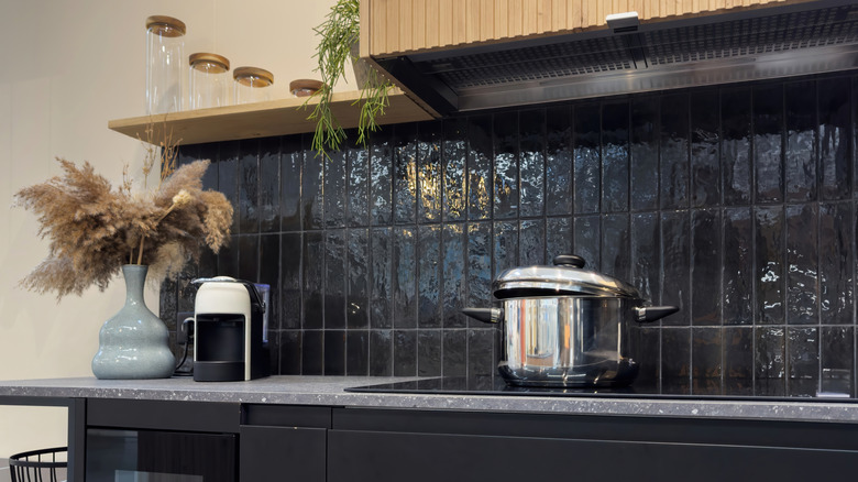A kitchen with a black and glossy vertical subway tile backsplash