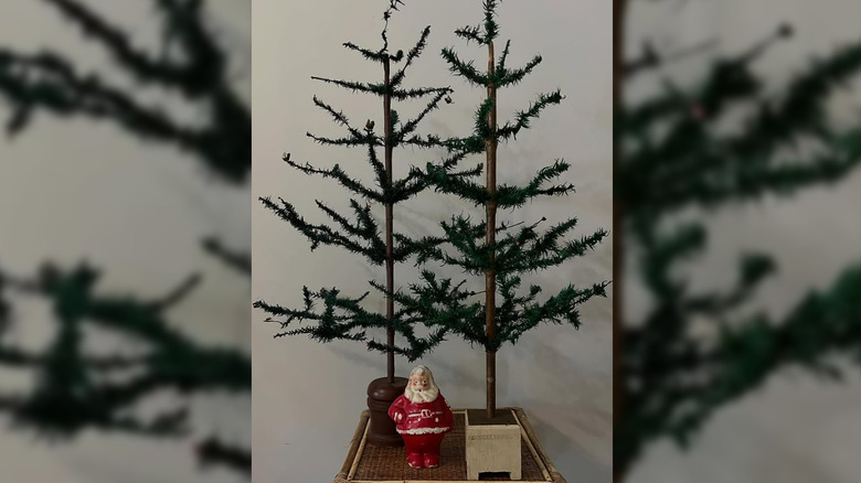 Two small feather trees next to a miniature Santa figurine