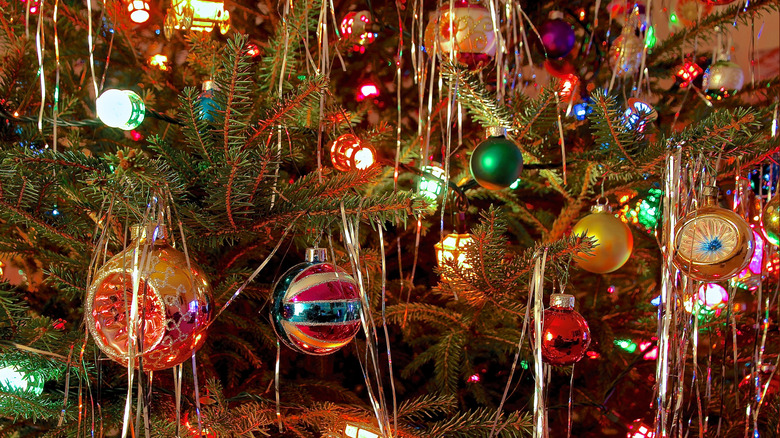 Retro ornaments, tinsel, and lights on a Christmas tree.