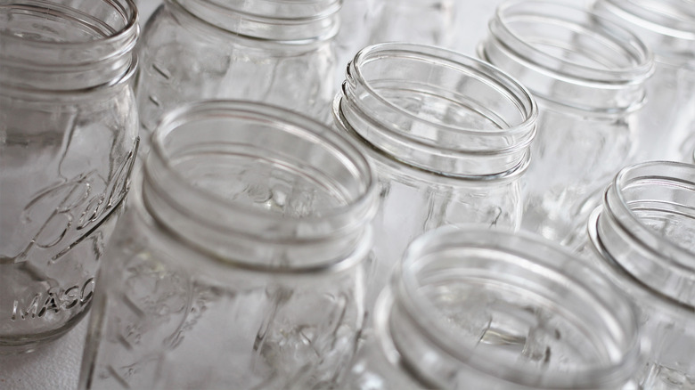 Open Mason jars lined up on a white surface