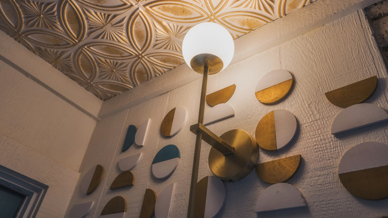 Brass globe sconce on wall with mid century tile sculpture