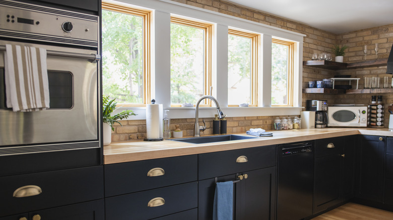 Modern kitchen with black cabinets and brick walls