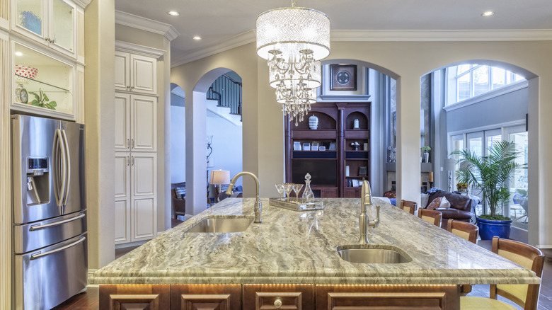 A elegant kitchen with stone countertops and a chandelier.