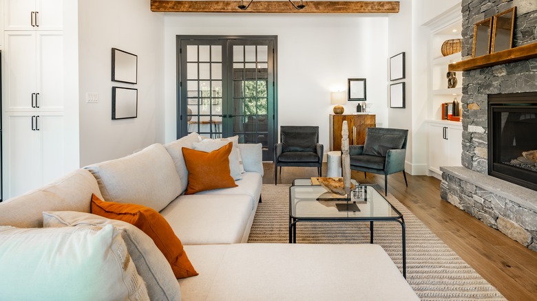 Modern Tuscan style living room with white walls, modern furniture, and stone fireplace