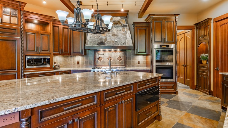 Tuscan style home kitchen with dark wood cabinets, detailed fixtures, and stone features