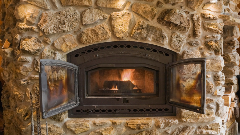Close-up of a fieldstone fireplace with wood burning inside