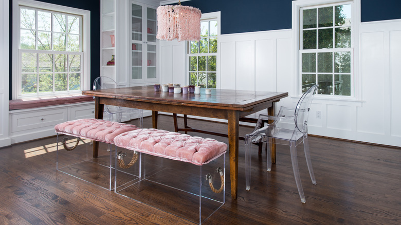 A wooden kitchen table with clear acrylic seating and pink accents