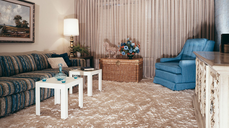 1960s living room featuring shag carpet, square modular end tables, sofa chair, and long, textured curtains