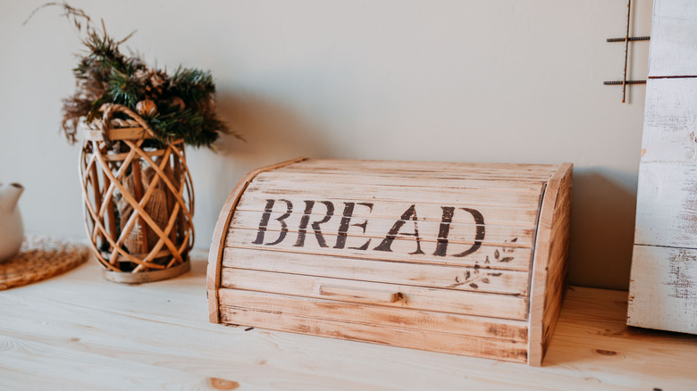 A kitchen counter with a closed breadbox next to a basket arrangement