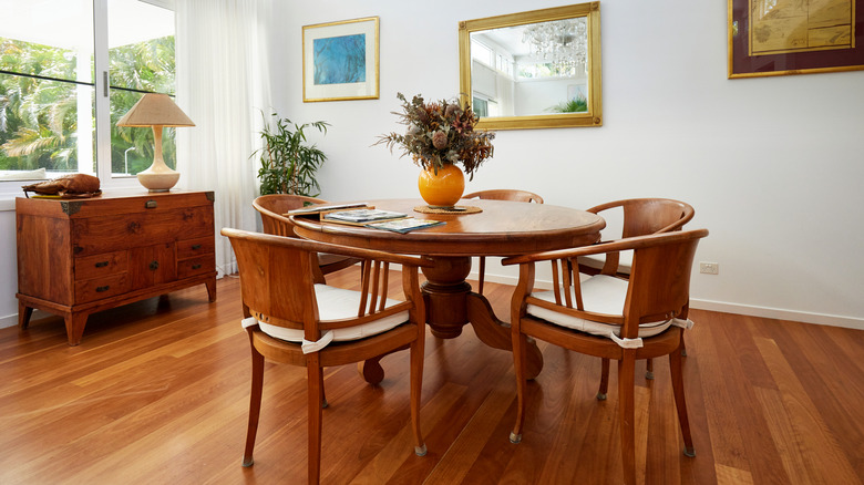 Dining room with round table and five chairs, a sideboard, and a large window.