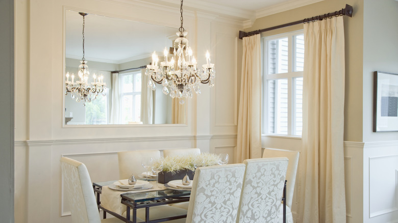 Dining room with crystal chandelier dangling over table.