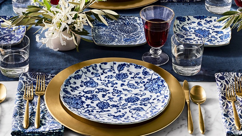 dinner table set with blue and white porcelain plates and gold accent flatware