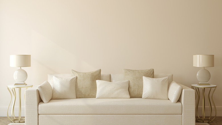 A beige living room with beige pillows, lamps, and couch
