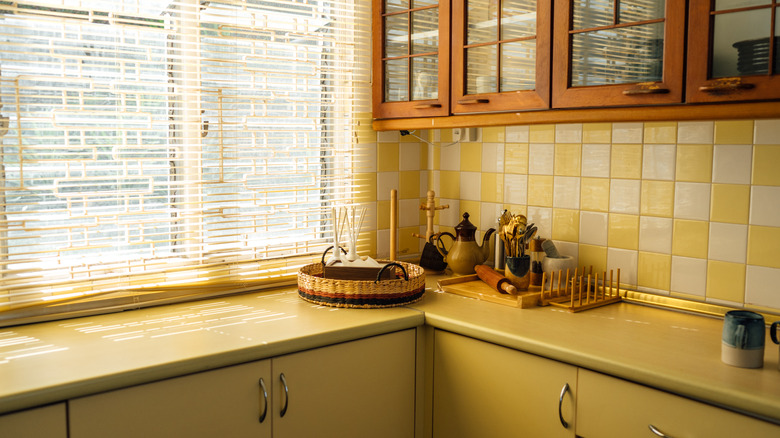 retro style kitchen with yellow cabinets, counters and checkered tile backsplash