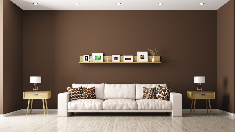 A cream sofa against a brown wall with light wood floors